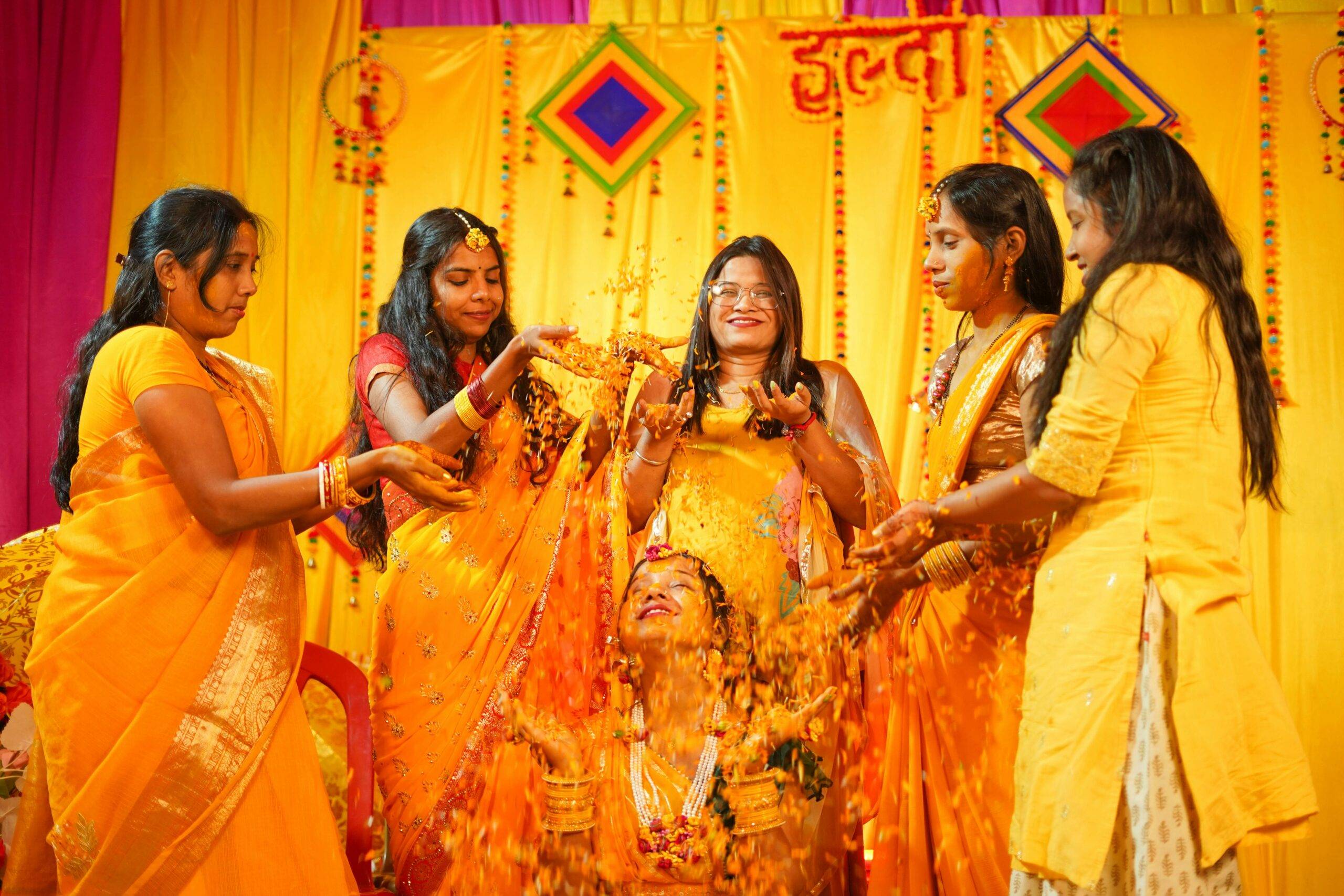 A joyful Haldi ceremony with Indian bridesmaids dressed in yellow and orange in Varanasi, India.